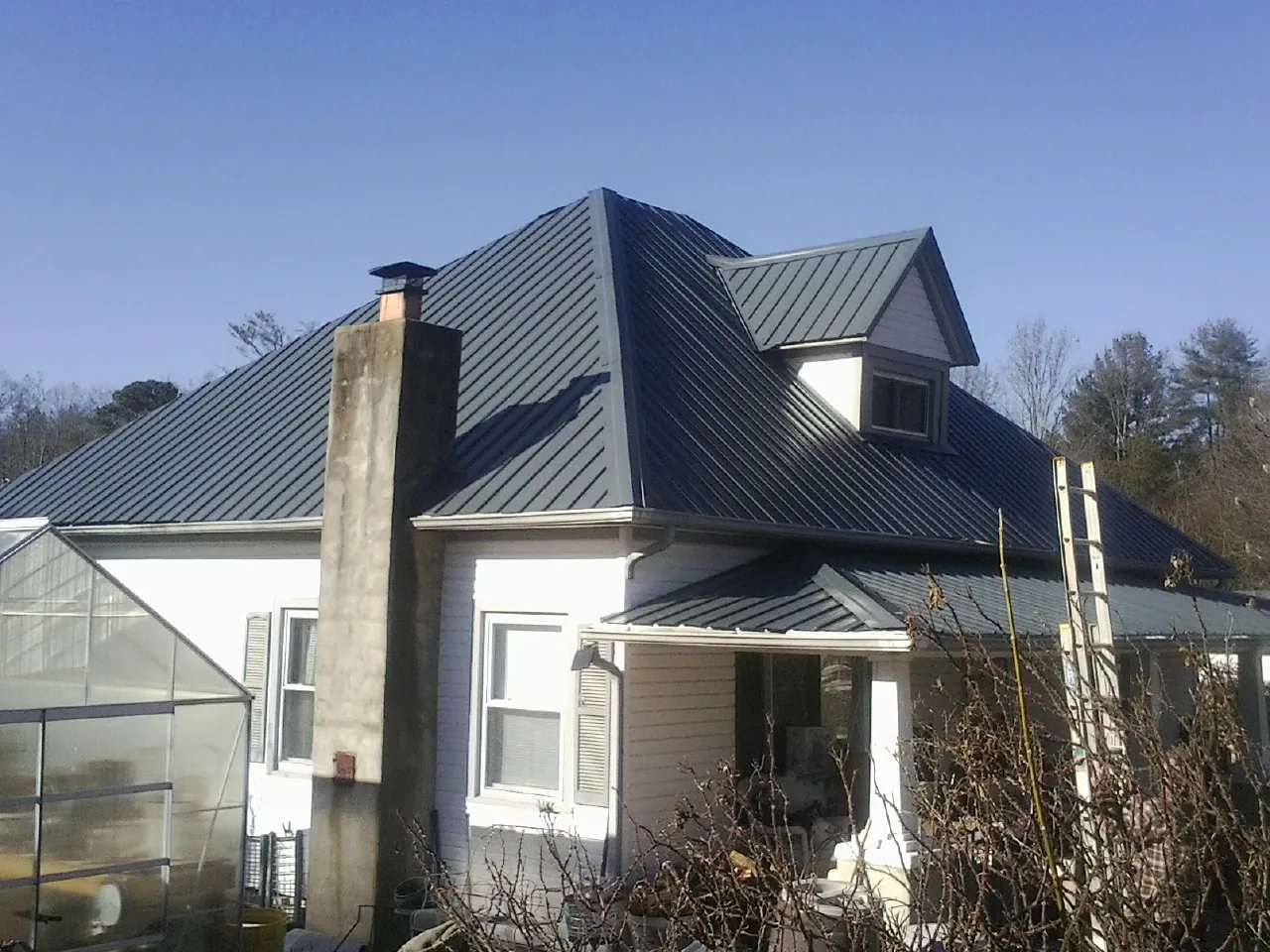 Dark blue standing seam metal roof on a white farmhouse with dormer — Slate & Tile Roof Repair by Roofing Brothers in Deersville