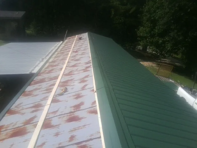 Old rusted panels beside newly installed green metal roofing — Wind Damage Roof Repair by Roofing Brothers in Deersville