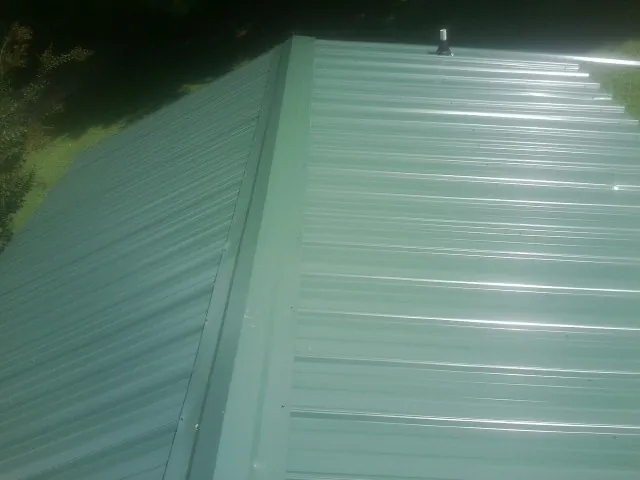 New green metal panels meeting at the ridge of a roof in Deersville