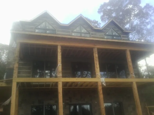 Dormers and porch framing on a large log home under construction — Roof Coating work by our crew in Deersville