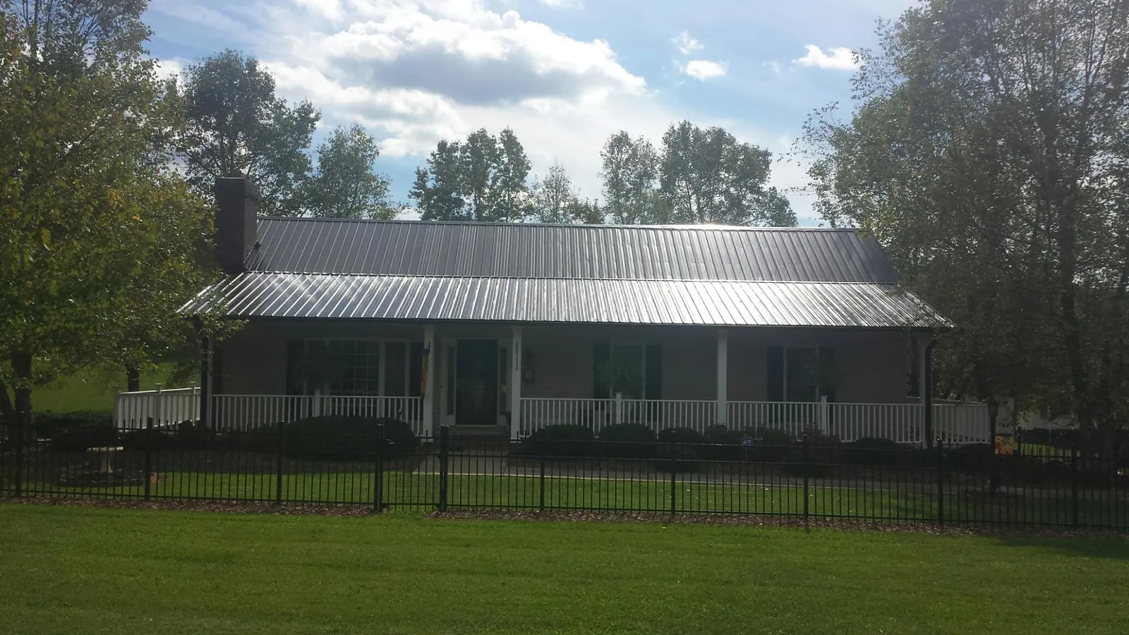 Gray metal roof on a brick ranch with a full width front porch — Gutter Guard Installation work by our crew in Deersville