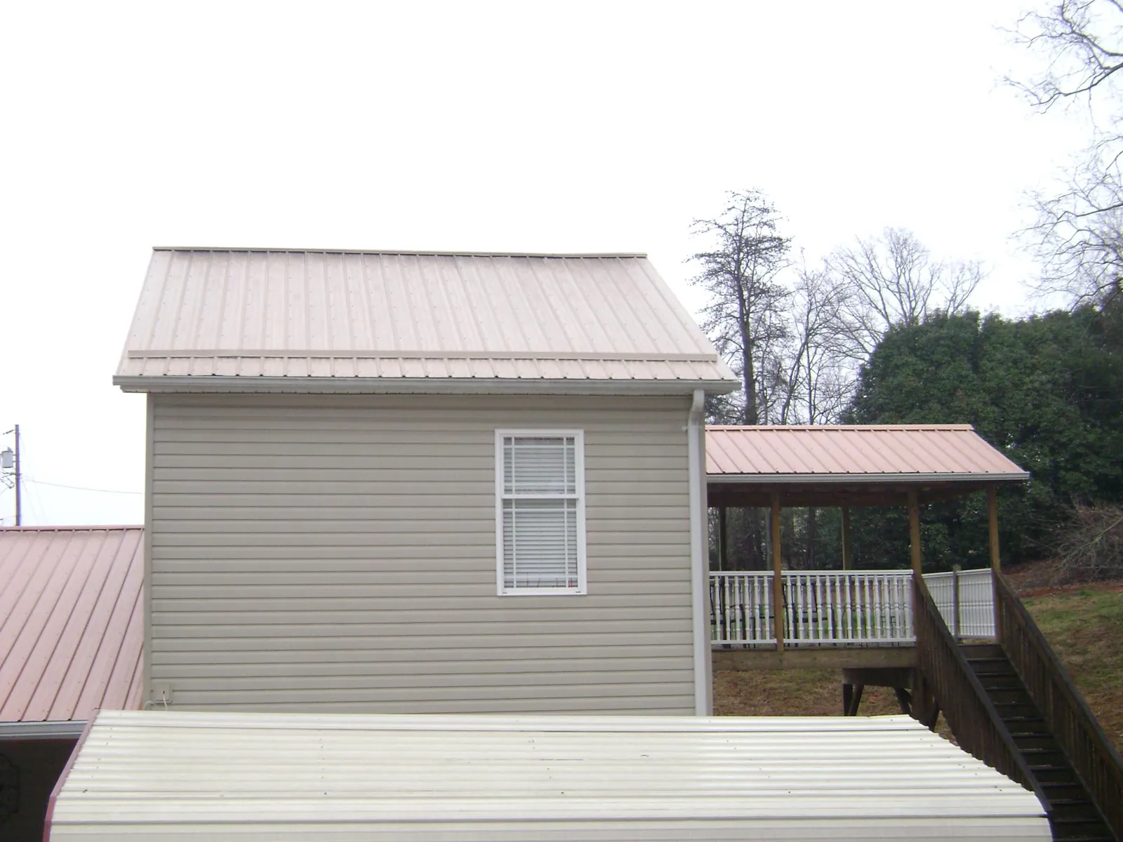 Tan metal roofs on a two story addition and attached porch, from a Roof Replacement job in Deersville