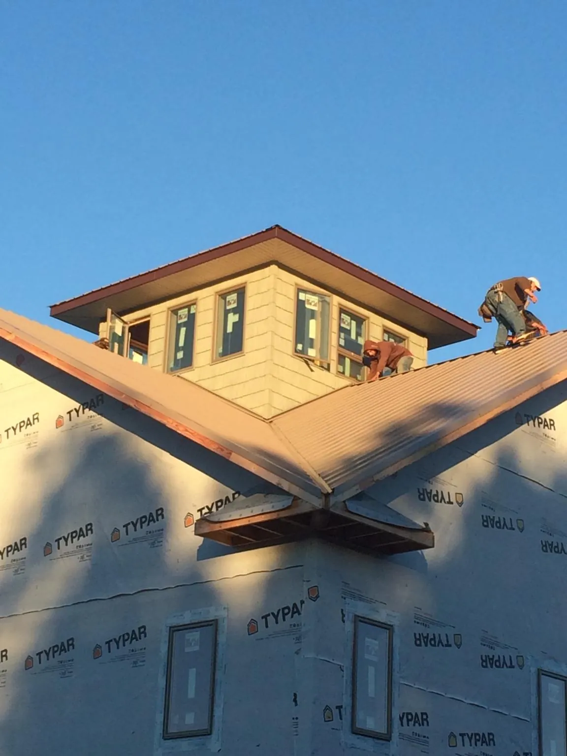 Roofers working around a rooftop cupola on a new metal roof at sunset — Roof Waterproofing in Deersville by Roofing Brothers